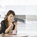 カフェでスマートフォンを使用する女性